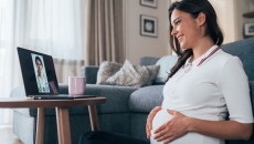
  Pregnant person sitting on the floor looking at a computer
