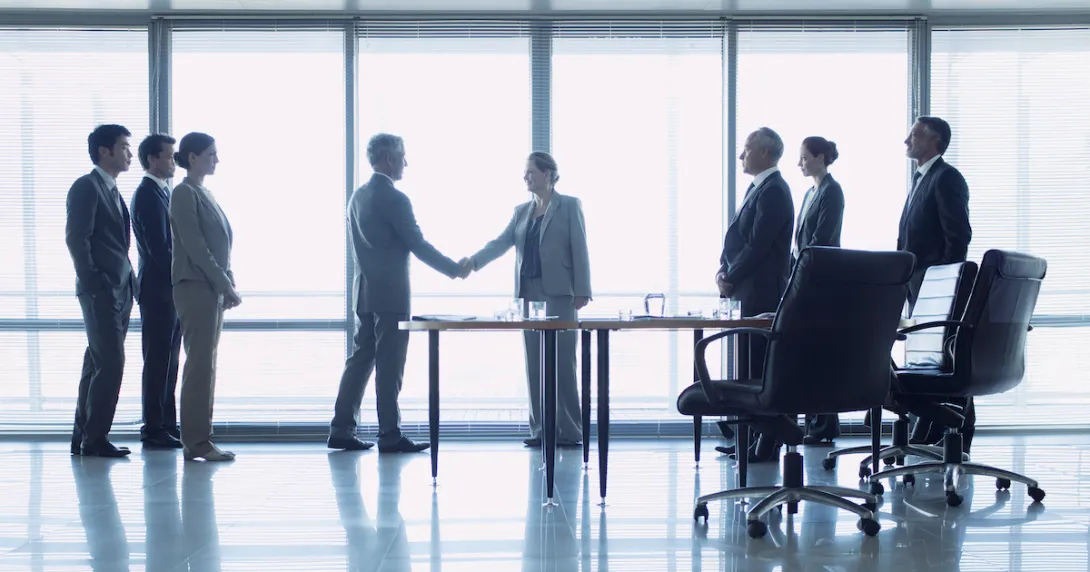 Two individuals shaking hands in front of a window while six other people watch Two individuals shaking hands in front of a window while six other people watch