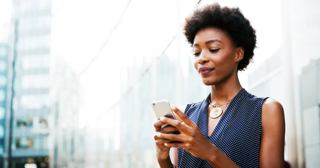 Women standing on a street looking at her phone Women standing on a street looking at her phone