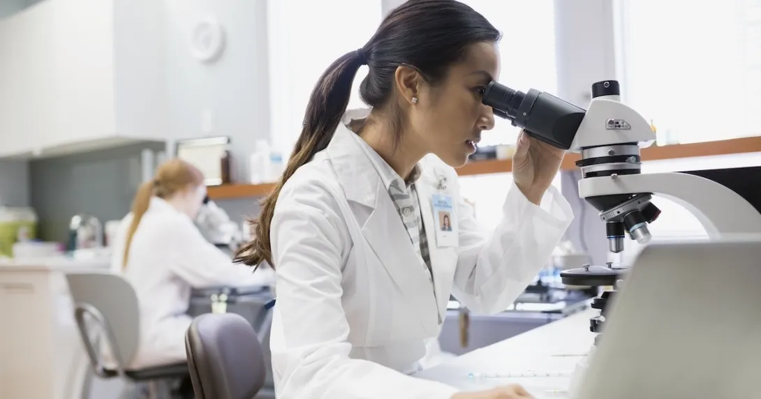 Healthcare professional looking into a microscope