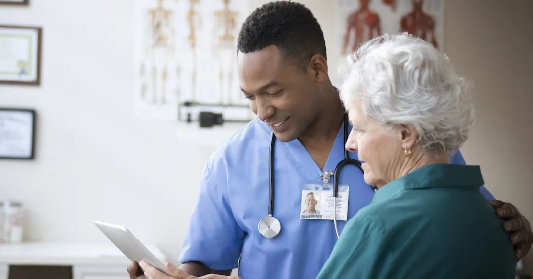 A doctor and a patient look at a tablet in his office.
A doctor and a patient look at a tablet in his office.