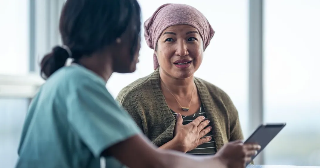 Healthcare provider sitting next to a patient with a scarf on their head while looking at a tablet
Healthcare provider sitting next to a patient with a scarf on their head while looking at a tablet