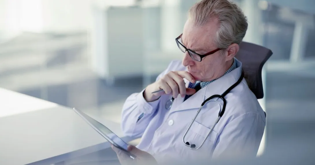 
  Physician sitting in a chair looking at a tablet
