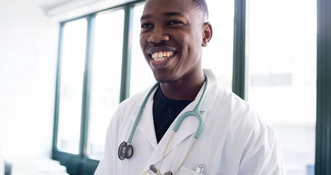 
  Healthcare provider smiling while wearing a lab coat and stethoscope 
