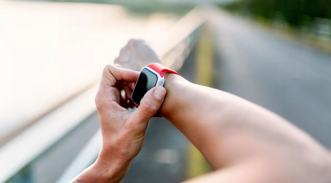A close up photo of a person using a wearable while on a running trail