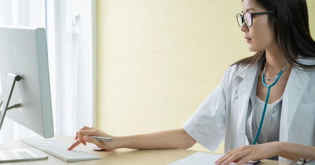 Healthcare provider sitting at a desk while looking at a computer Healthcare provider sitting at a desk while looking at a computer